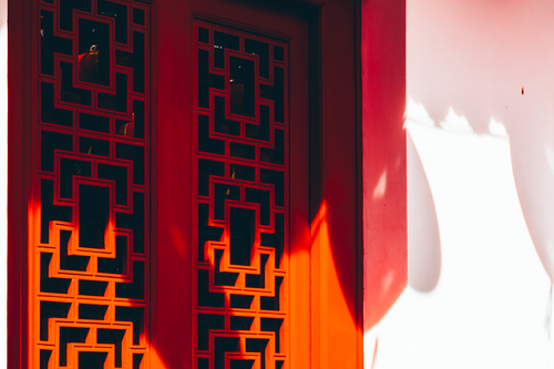 Free Vibrant red lattice window with geometric patterns in warm sunlight, casting shadows. Stock Photo
