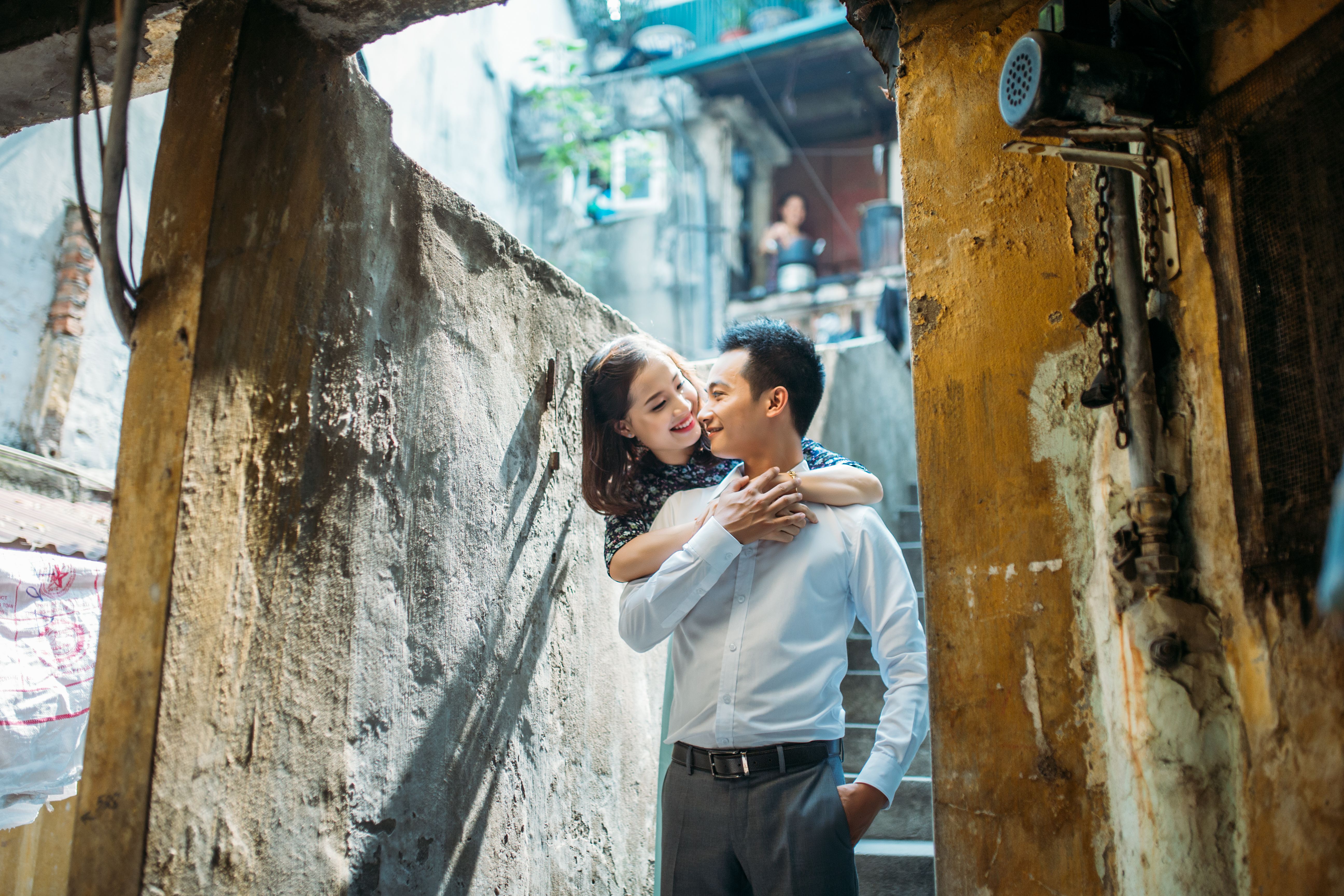 Young couple in a loving embrace amid urban backstreet, symbolizing romance and connection.