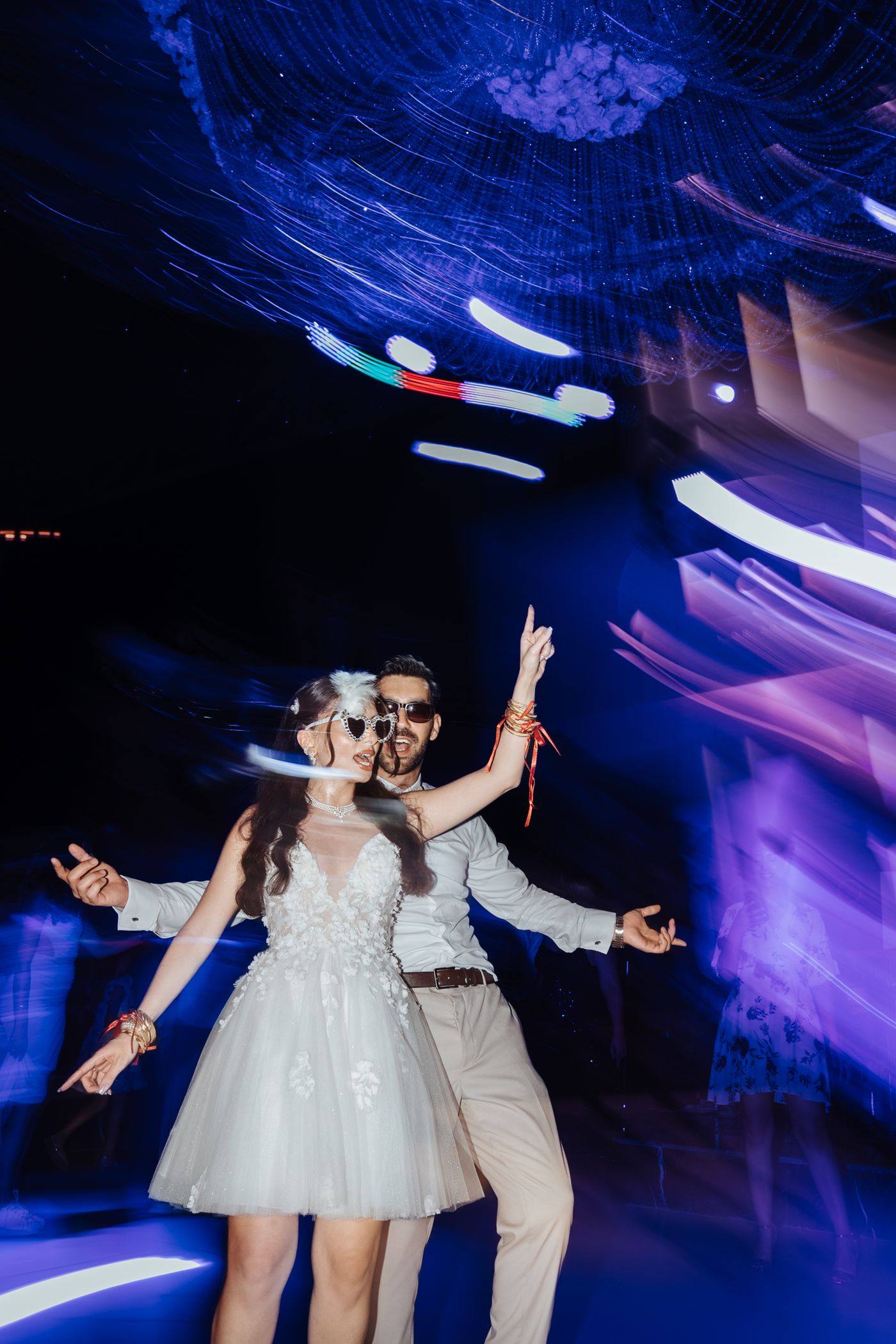 Wedding couple moving through colorful dance-floor lights