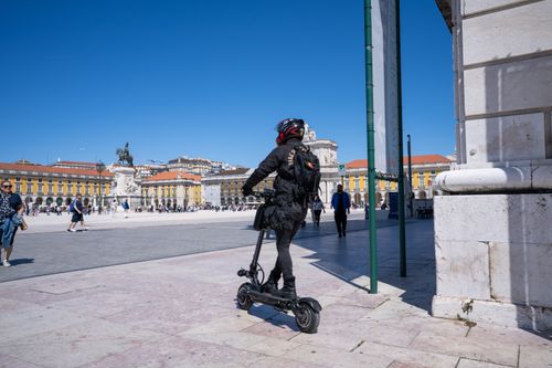 Free A person riding an electric scooter in Praça do Comércio, Lisbon on a sunny day. Stock Photo