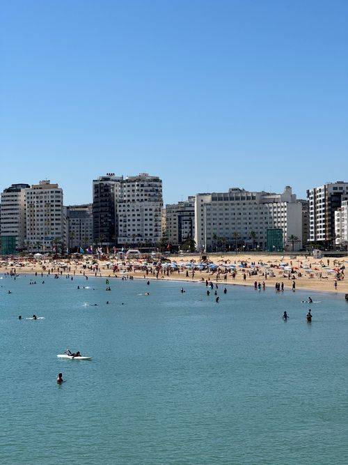 Free A sunny day at Tangier beach with people enjoying the water and skyline backdrop. Stock Photo