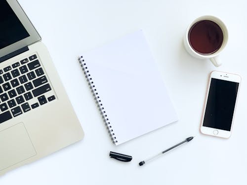 Free Macbook  Beside White Notebook And Pen Stock Photo