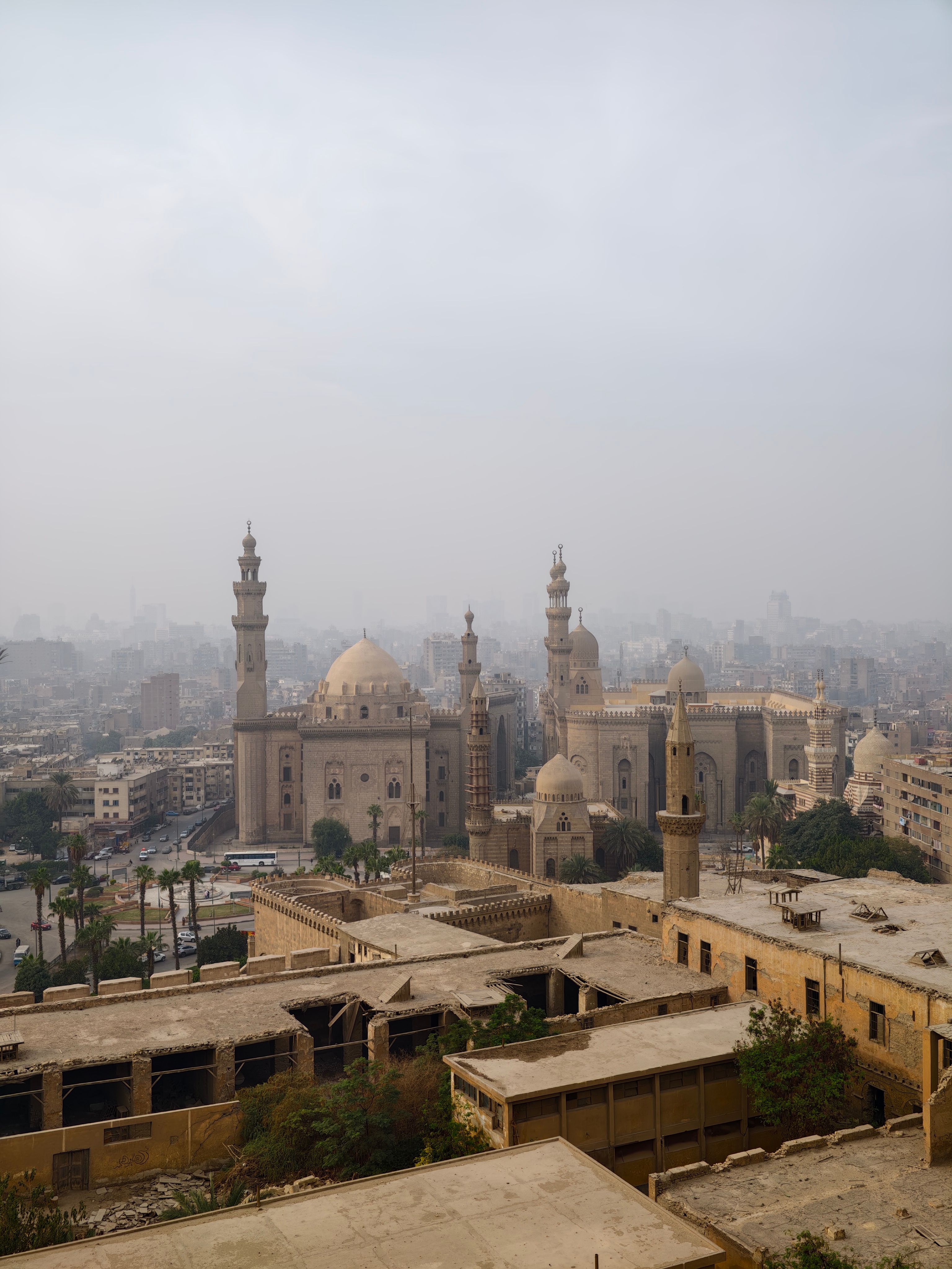 Aerial view of Cairo with iconic mosques under a hazy sky.