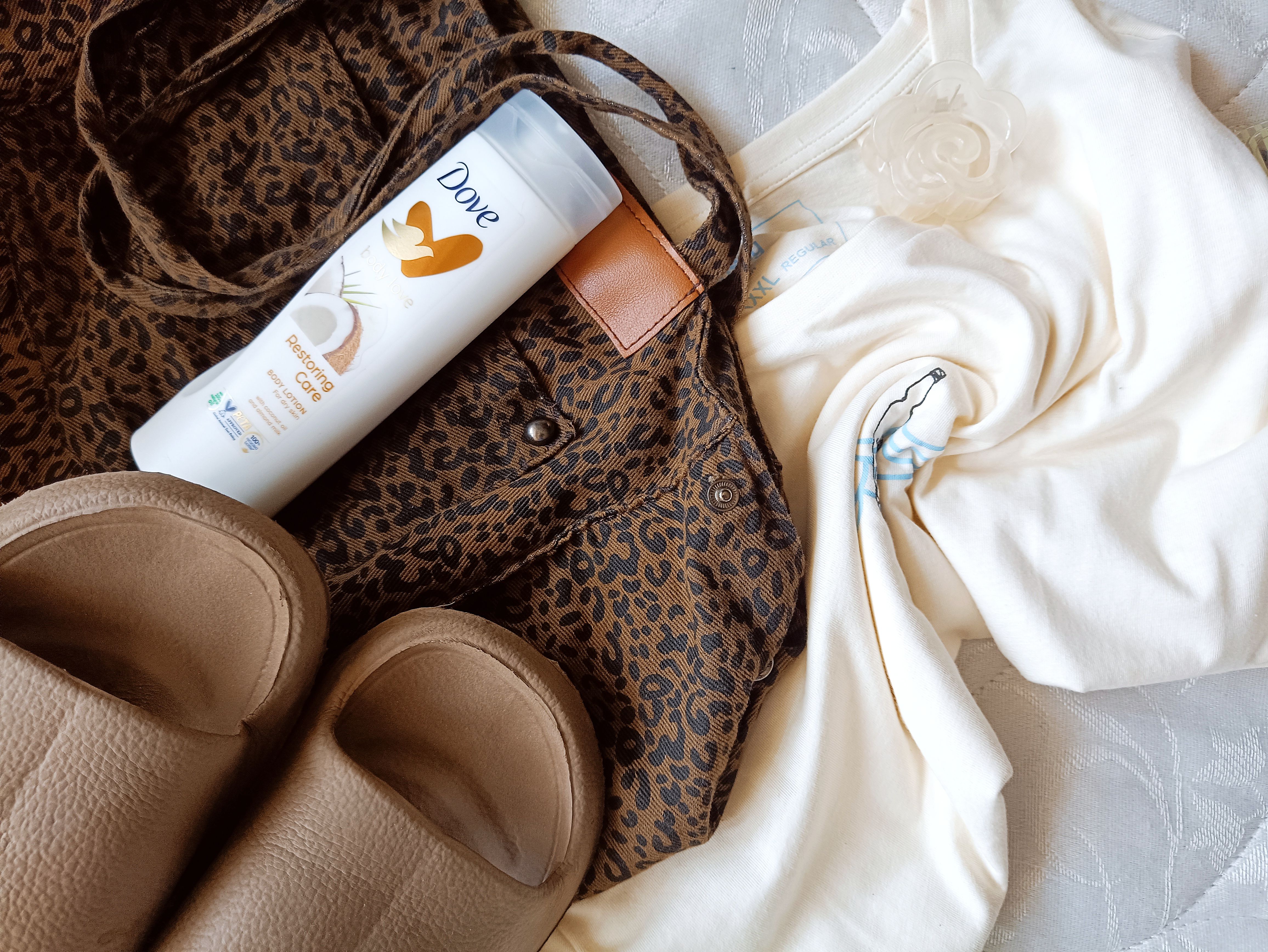 Fotomural Una imagen plana que muestra artículos de moda y cuidado personal, incluyendo un bolso con estampado de leopardo, crema y zapatillas.