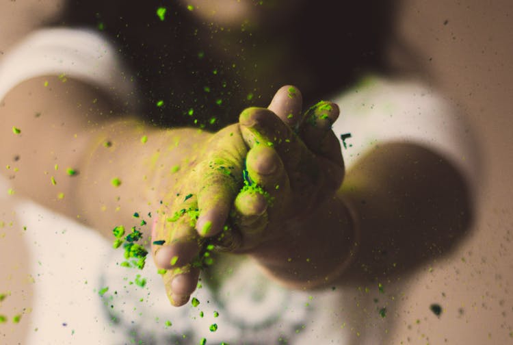 Person Rubbing Green Powder On Their Hands