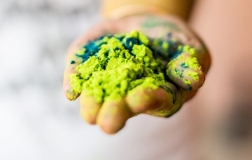 Free A close-up of a hand holding vibrant green and blue Holi powder, symbolizing festival celebration. Stock Photo