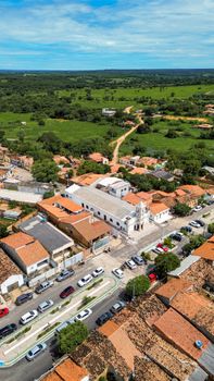 Charming aerial view of a quaint town showcasing a central church, roof tiles, and lush surrounding greenery.