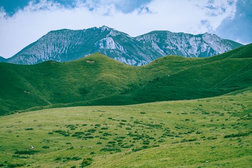 Free Beautiful mountain view with rolling green hills under a bright sky, perfect for nature enthusiasts. Stock Photo
