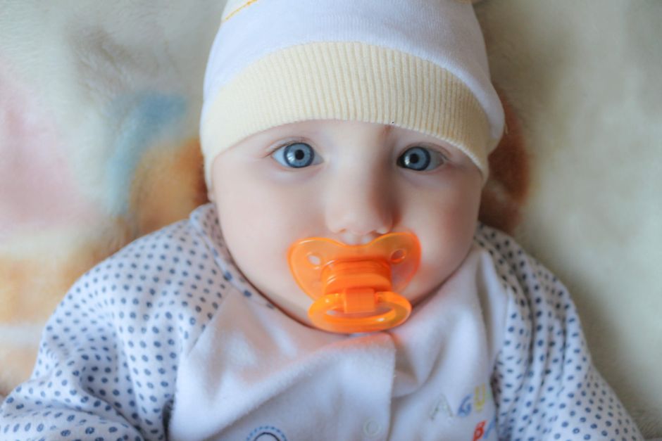 Bebê usando chapéu e chupeta