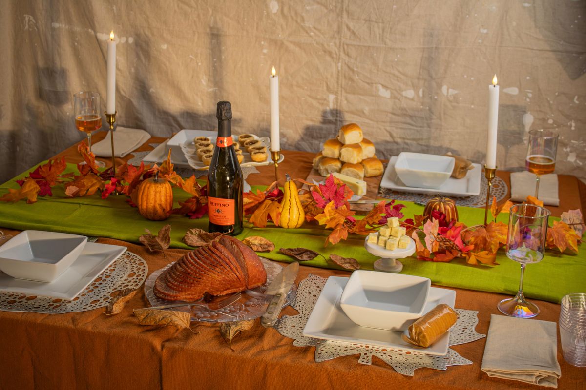 Thanksgiving table setting ideas with a warm autumn-themed dinner table with seasonal decorations, candles, and food