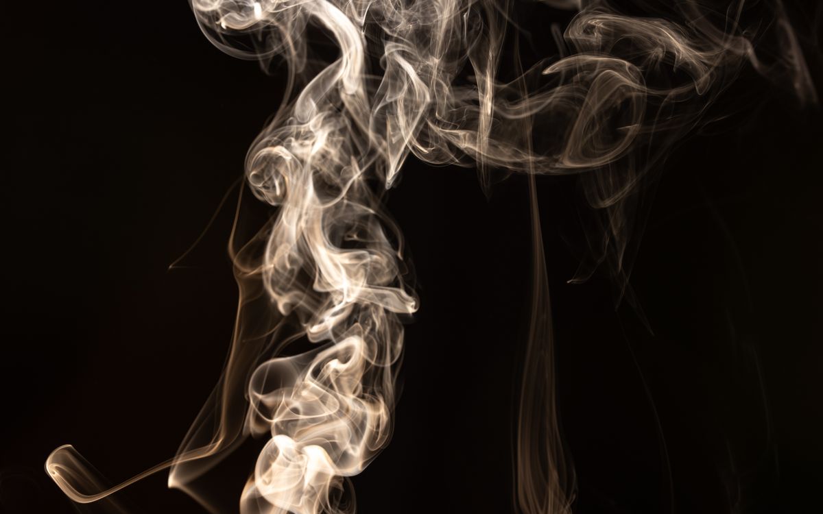 Vivid capture of white smoke swirling against a dark backdrop, creating mysterious organic shapes.