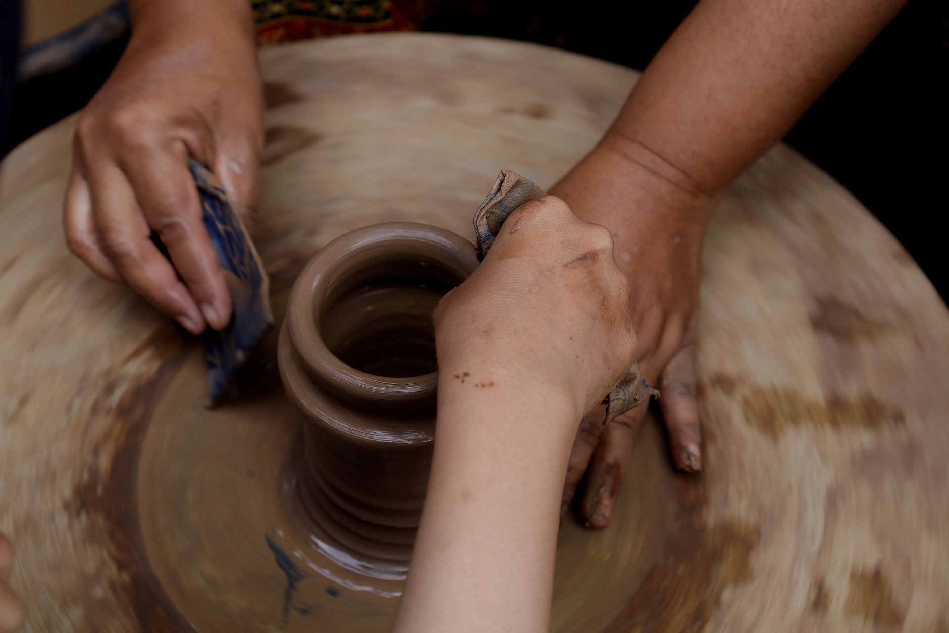 Close-up of hands sculpting clay pottery on a wheel, pottery-making art.