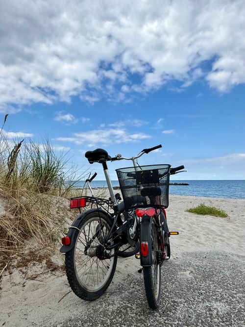 Free A bicycle with a basket parked beside a coastal path, under a bright blue sky on a sunny day. Stock Photo
