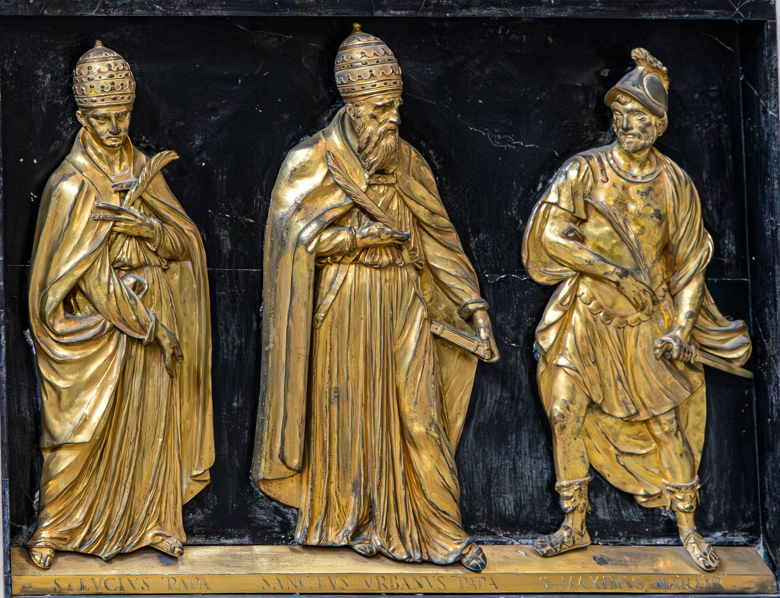 Intricate golden relief sculpture of historical figures in Rome, Italy, showcasing elaborate artistry.