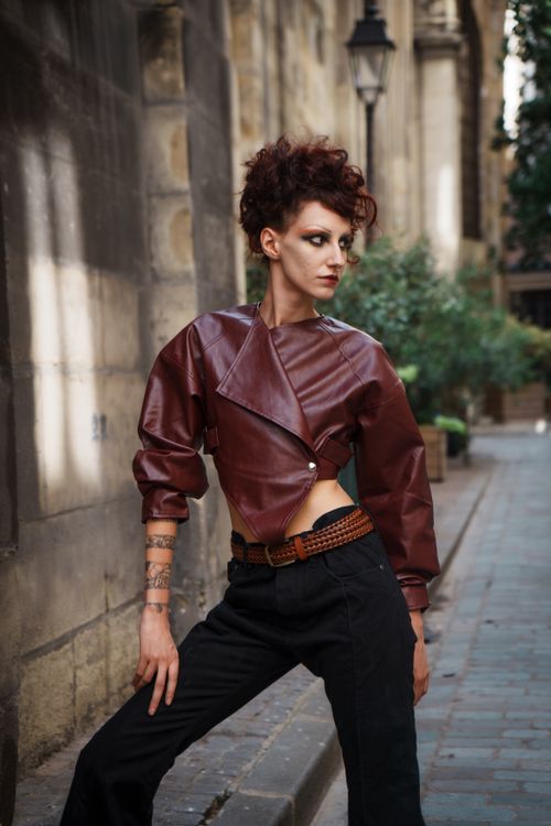 Free Stylish woman in edgy leather jacket poses confidently on a city street in daylight. Stock Photo