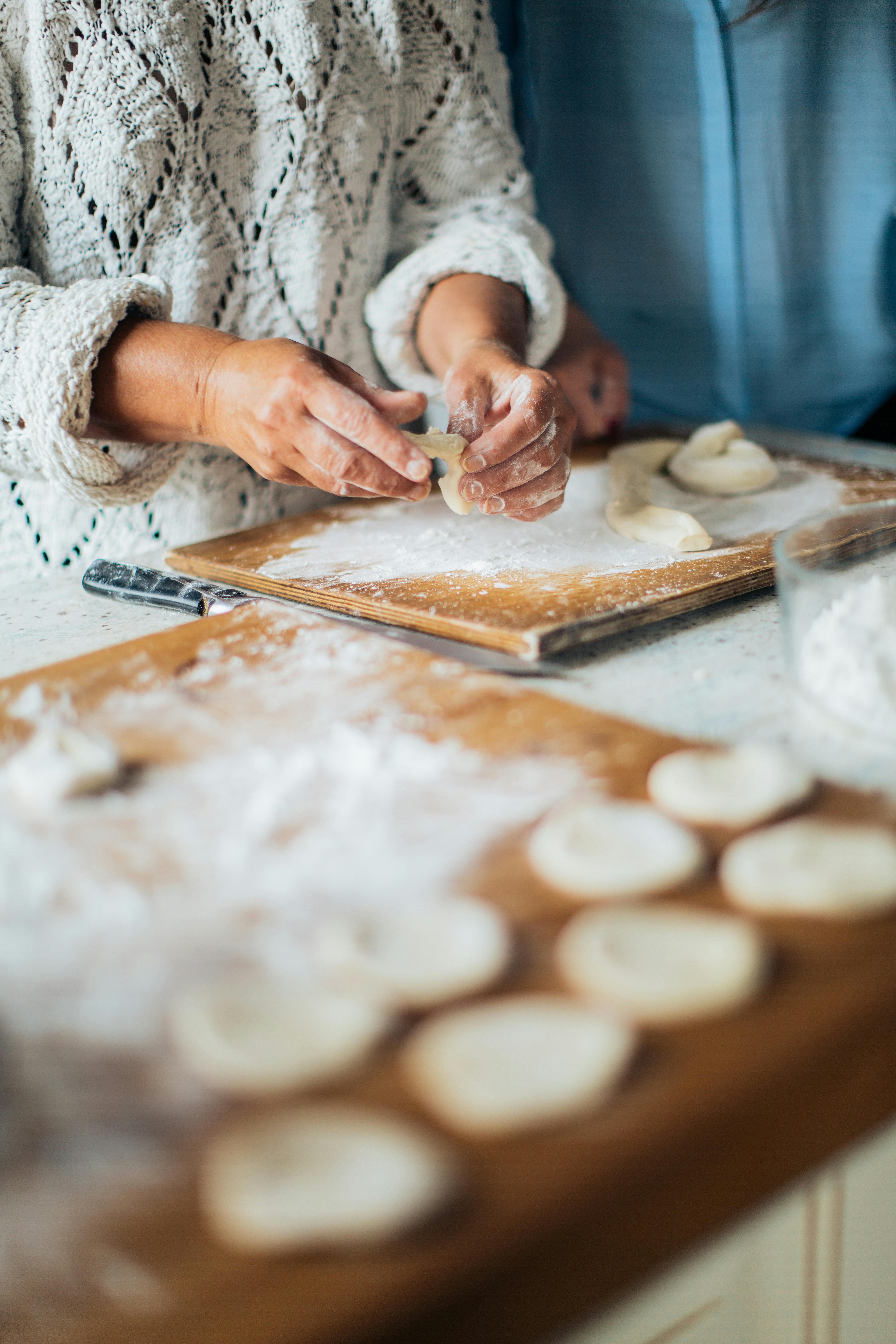 person holding white dough on brown wooden table