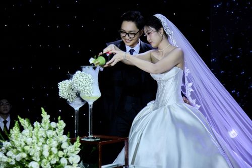 Free Bride and groom toasting with champagne at a wedding with floral decor and a starry backdrop. Stock Photo