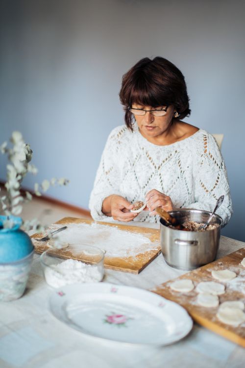 Free Woman preparing homemade dumplings in a cozy kitchen setting. Stock Photo