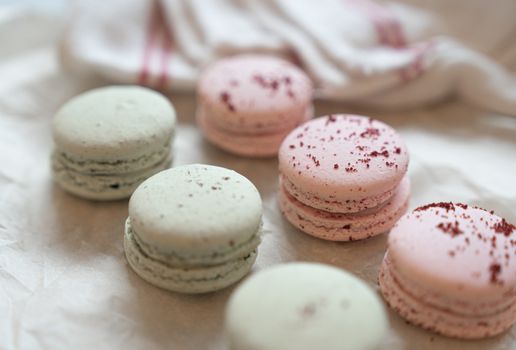 Assorted green and pink macarons on parchment paper, perfect for fine dining and dessert themes.