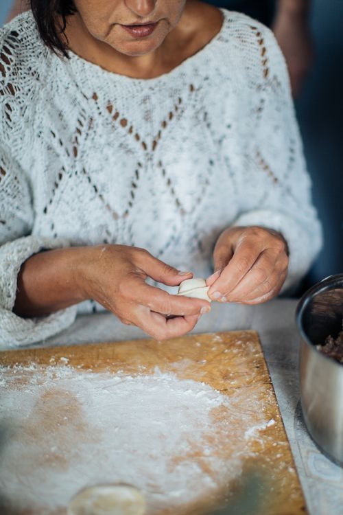 Free An adult woman is crafting traditional dumplings on a floured board, emphasizing handmade culinary skills. Stock Photo