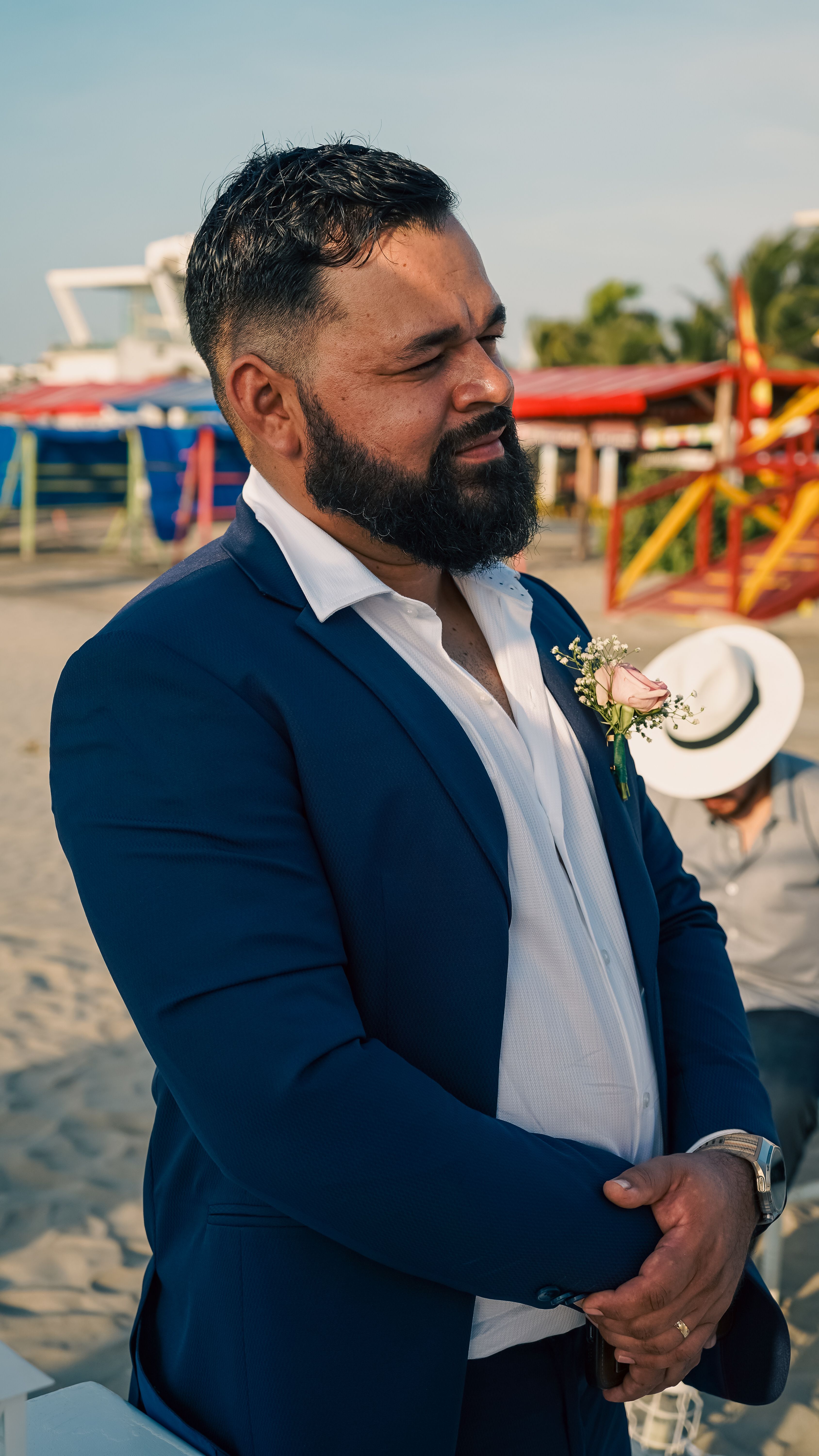 A man in a navy suit at a beach wedding, looking thoughtful and serene. - men's dress for different occasions