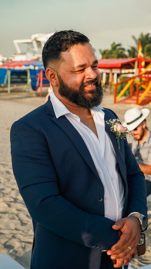 Free A groom in a blue suit smiles on a sunny beach day, capturing a moment of joy and celebration. Stock Photo