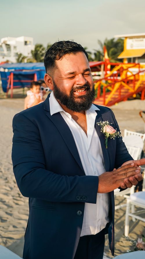 Free A happy groom in a blue suit smiling at an outdoor beach wedding. Stock Photo