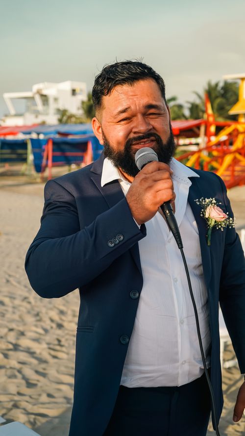 Free A man in a blue suit gives a speech on a sunny beach, holding a microphone. Stock Photo
