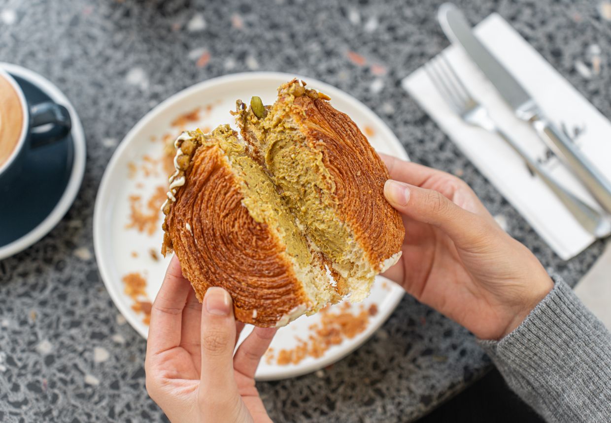 A half-eaten croissant beside a fresh coffee at a café table