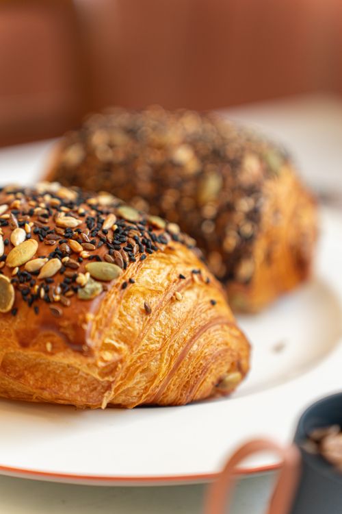 Free Delicious seed-crusted croissants on a plate, perfect for breakfast or brunch. Stock Photo