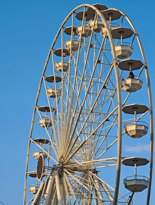 Free A majestic Ferris wheel soaring into a bright blue sky, capturing leisure and adventure. Stock Photo