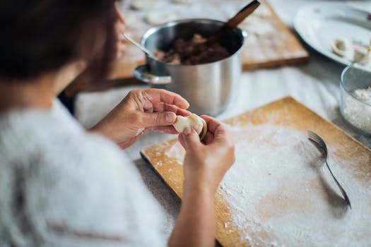 Close-up of a woman skillfully preparing traditional Russian pelmeni on a wooden board.