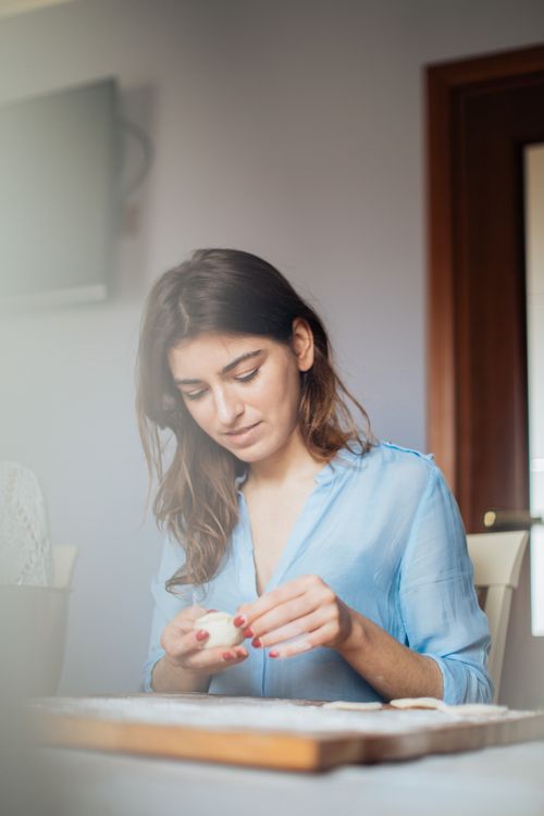 Free A woman skillfully prepares traditional pastries on a wooden board at home. Stock Photo