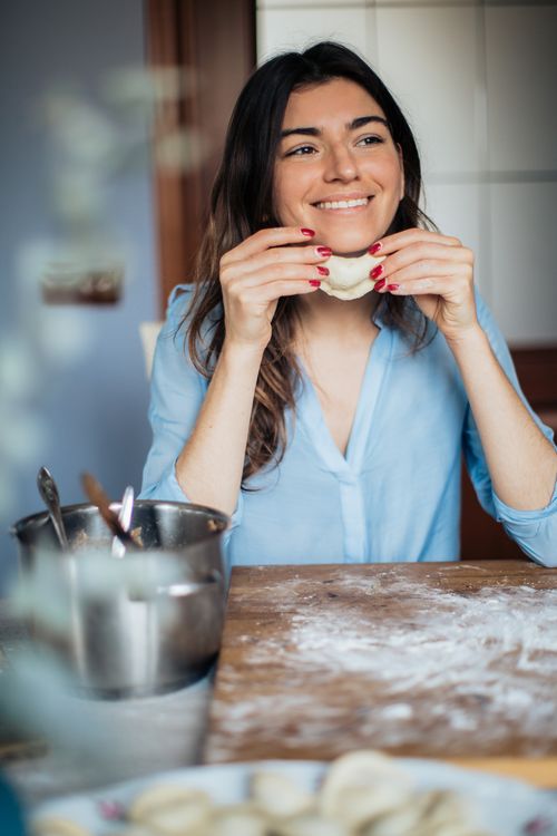 Free Smiling woman preparing homemade dumplings in a cozy kitchen setting. Stock Photo