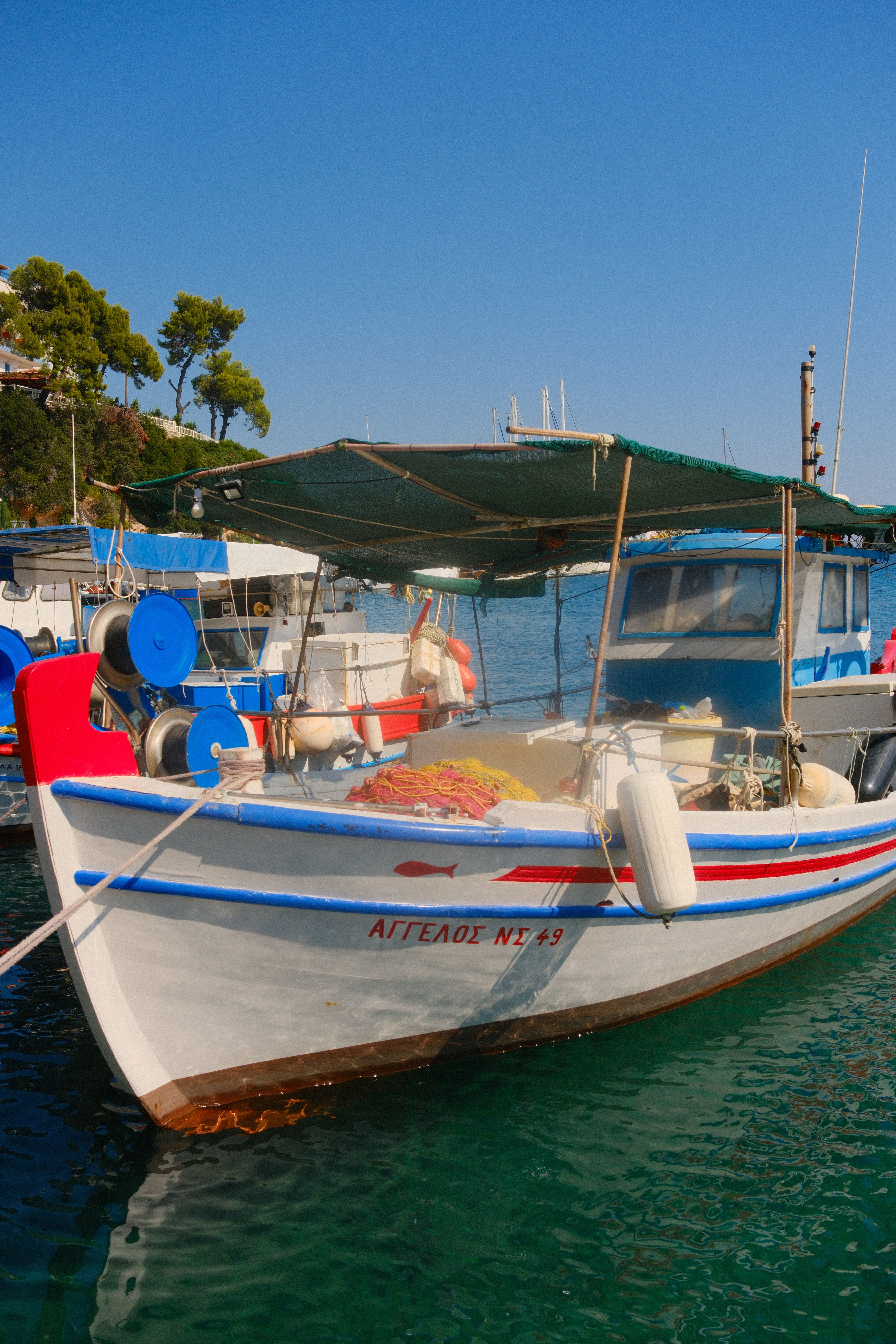 Colorful fishing boats docked in a serene Greek harbor on a sunny day.