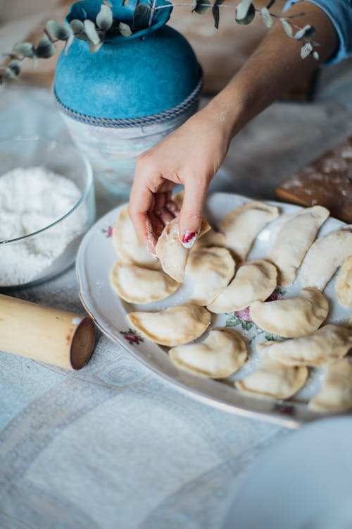 Person Putting Pelmeni in White Ceramic Plate