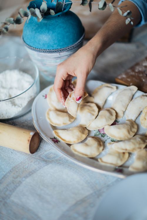 Free A close-up of a woman's hands making traditional pelmeni with dough and flour. Stock Photo