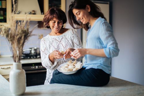 Free A mother and daughter enjoy making dumplings in a cozy indoor kitchen setting. Stock Photo