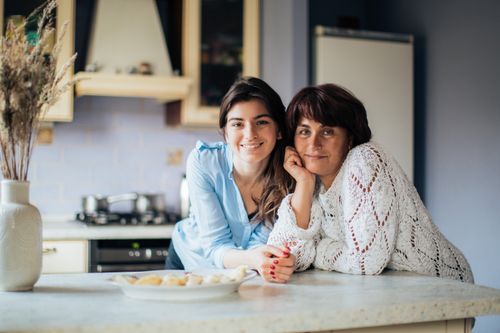Free A mother and daughter bonding in the kitchen, smiling and enjoying their time together. Stock Photo