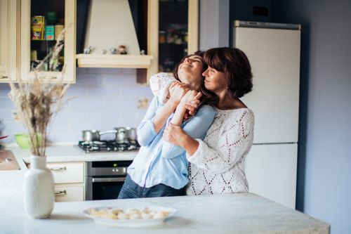 Free A tender moment between a mother and daughter in a cozy kitchen setting. Stock Photo