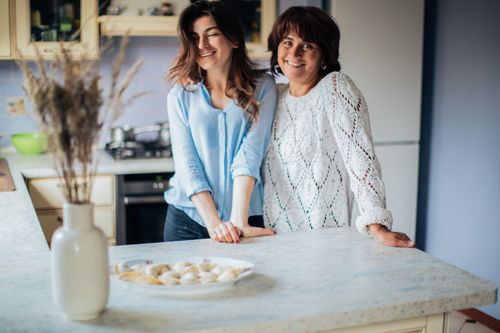 Free Portrait of a happy mother and daughter at home with traditional Russian dumplings. Stock Photo