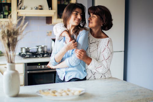 Woman In White Long Sleeve Hugging Her Daughter