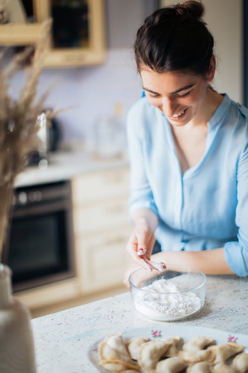 Woman in Blue Long Sleeve Shirt Touching Flour in Bowl