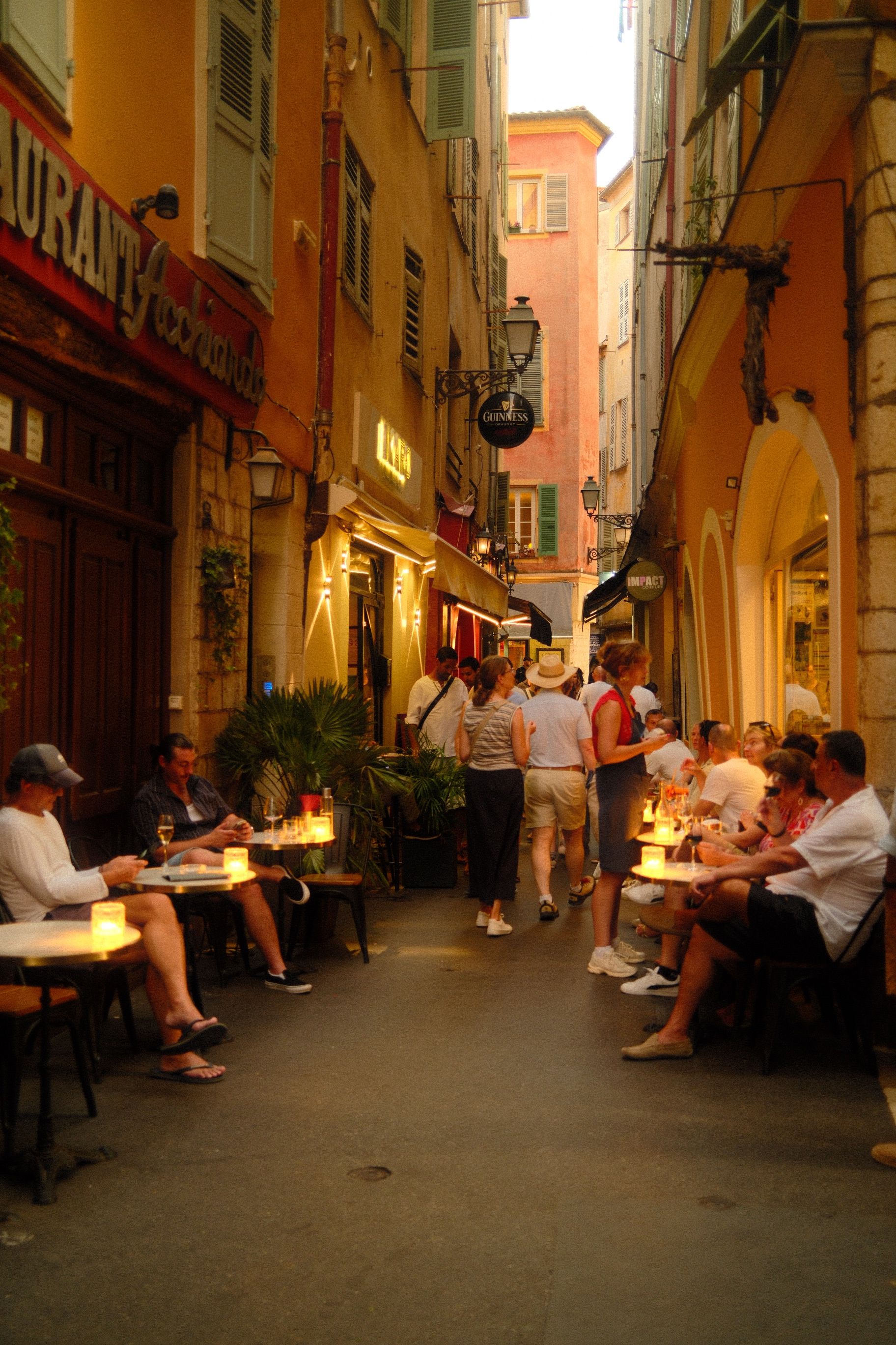 Cozy outdoor dining in a narrow street of Nice, France, during sunset, capturing the lively Mediterranean ambiance.