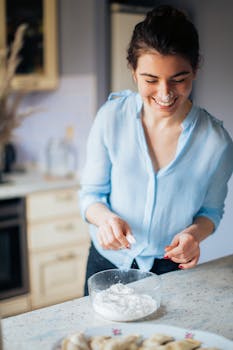 A happy woman making traditional Russian pelmeni at home.