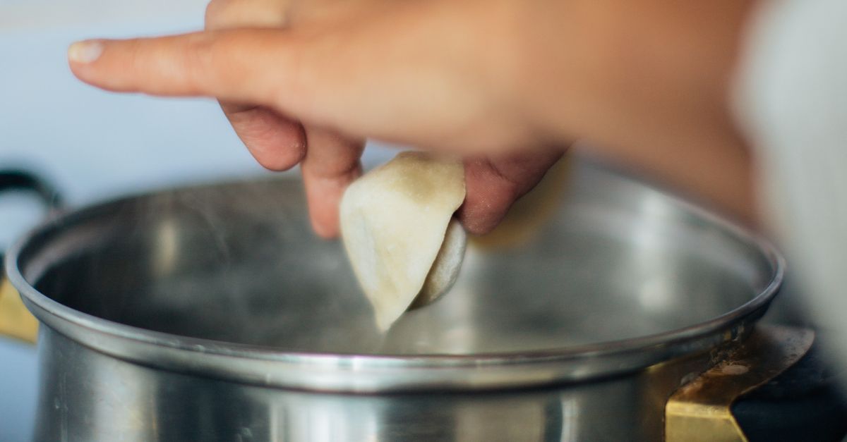 Rüyada Aileyle Yemek Yemek - Rüya Tabiri ve Anlamı - Close-up of hands cooking dumplings over a steaming pot, showcasing traditional culinary techniques.