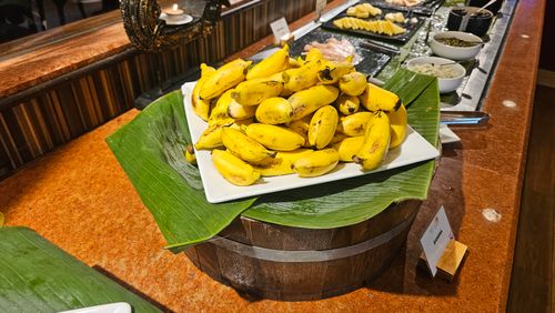 Free A vibrant display of bananas on a buffet table with rustic decor and banana leaves. Stock Photo