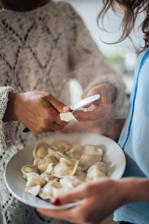 Free Two women preparing steaming pelmeni dumplings in a cozy indoor setting. Stock Photo
