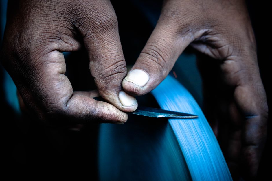 Hands sharpening a blade on a grinding wheel — how to sharpen hedge clippers using a file and whetstone in Surrey BC