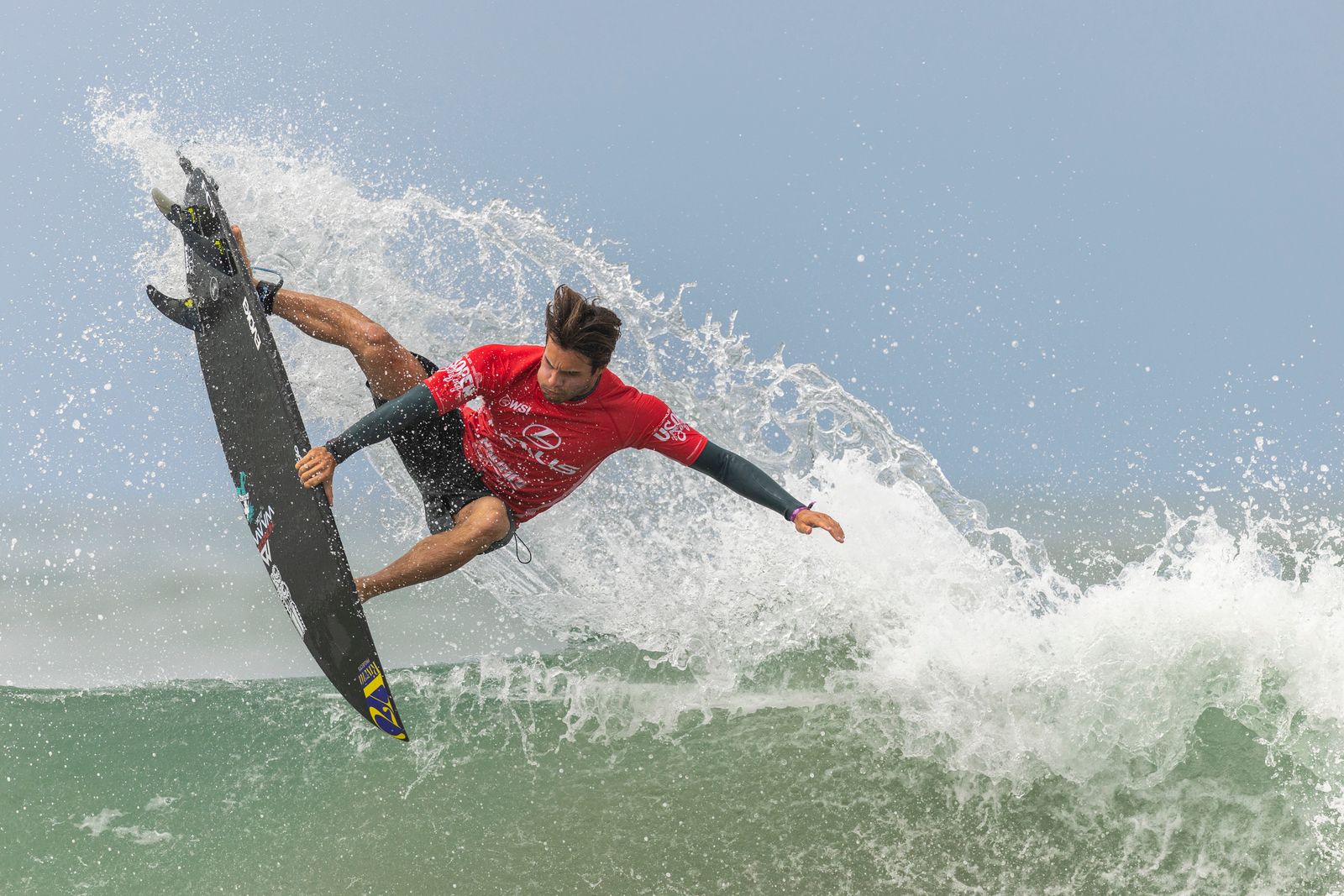 Surf au Maroc 2026 — surfeur sur une longue vague droite à Anchor Point Taghazout avec les contreforts de l'Atlas en arrière-plan